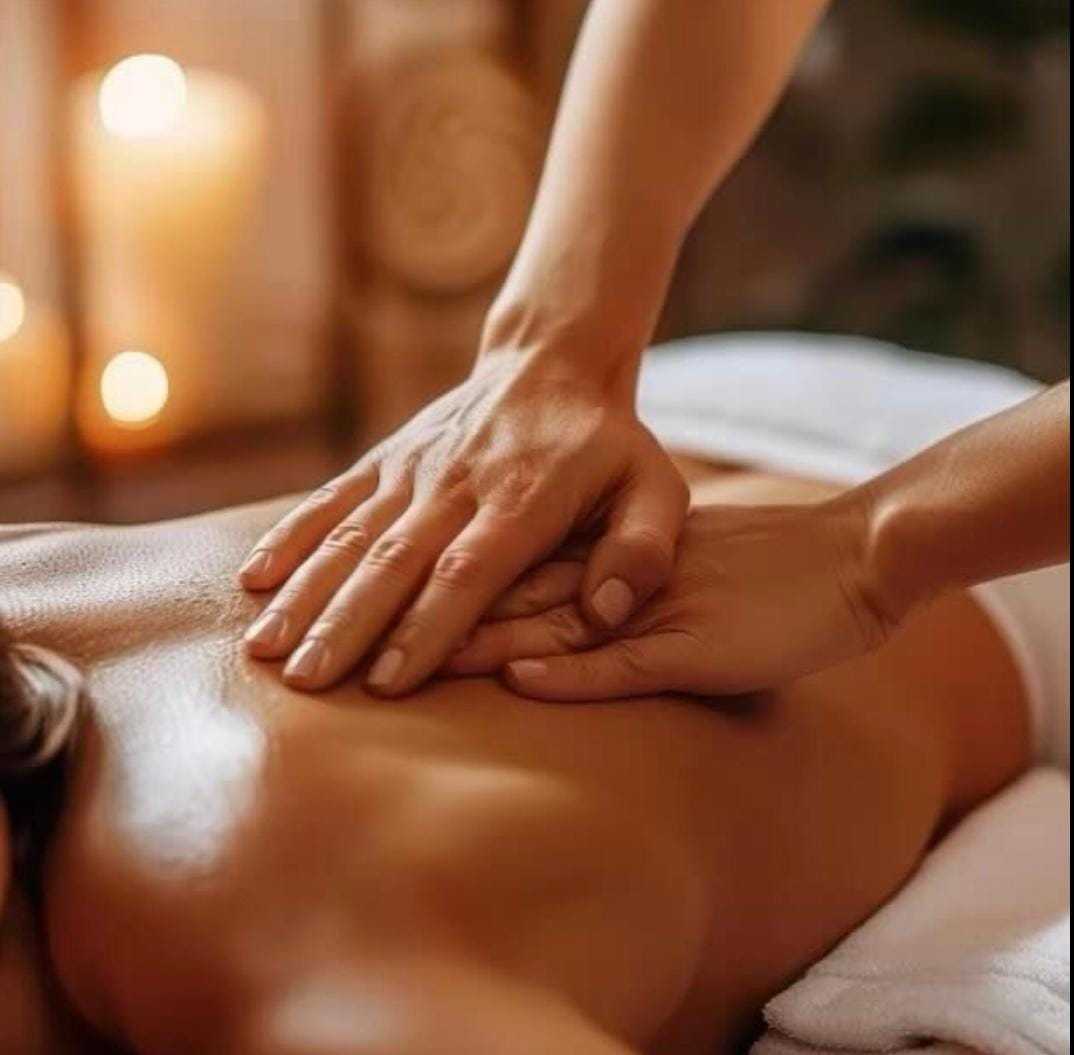 Person receiving relaxing back massage in serene spa setting with candles.