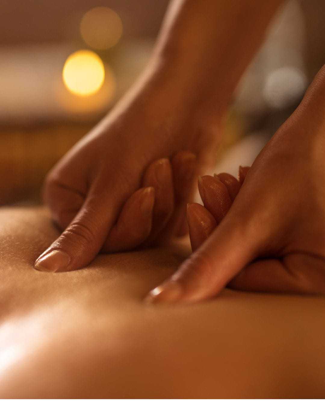 Person receiving a massage with gentle, dim lighting for relaxation.