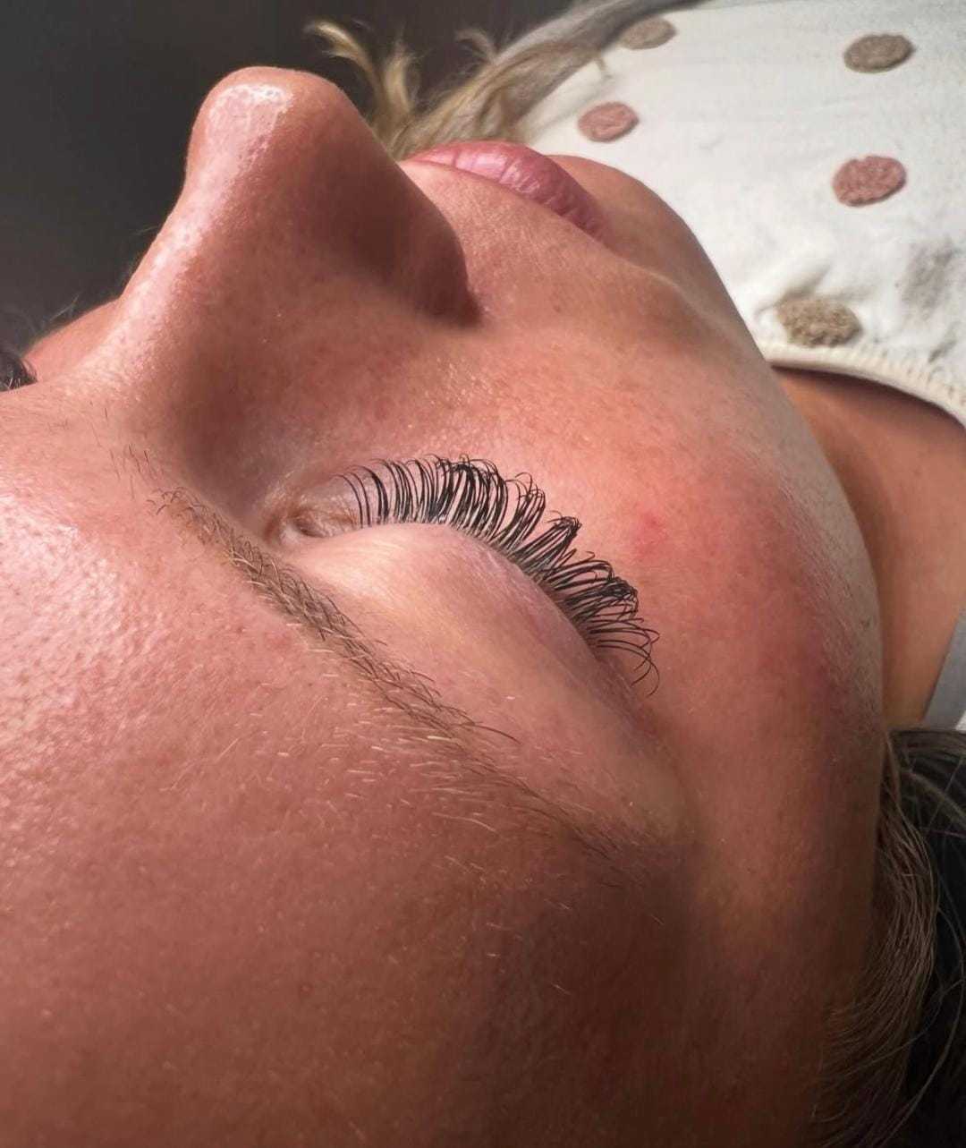 Person with closed eyes, showcasing freshly styled long eyelashes.