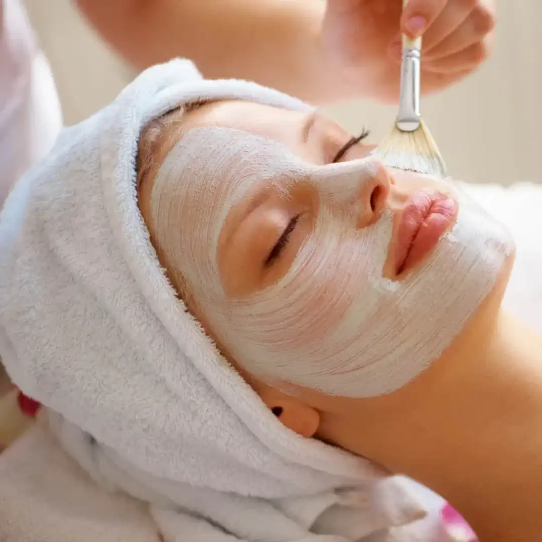 Person relaxing with a facial mask applied in a spa setting.