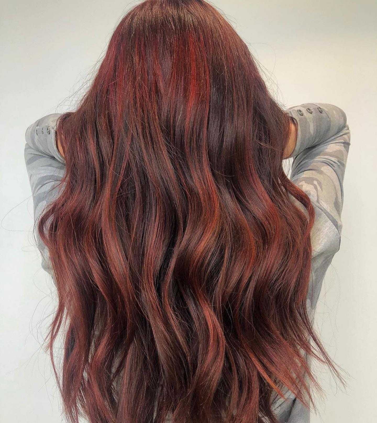 Long, wavy, rich auburn hair from the back against a neutral background.