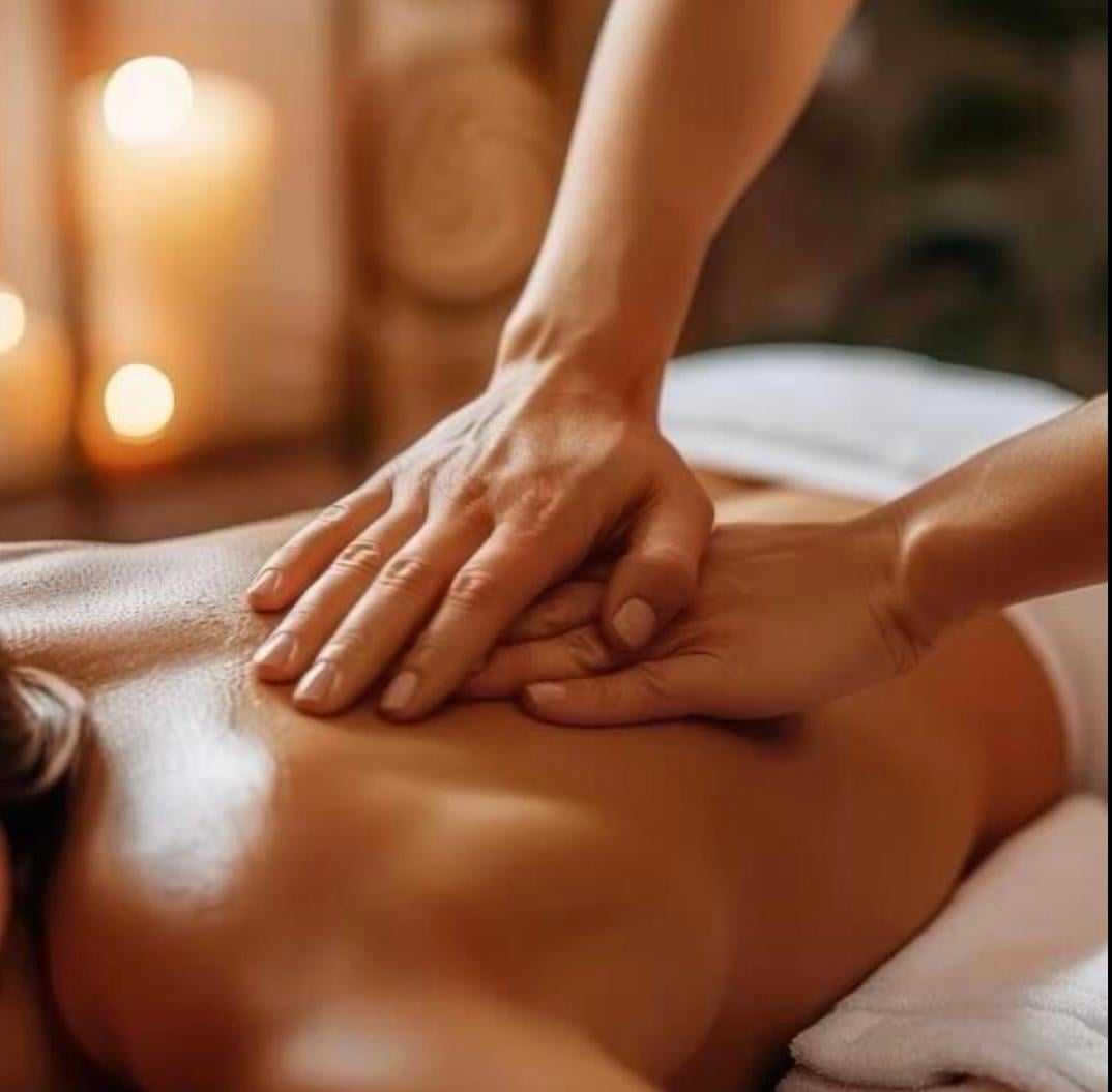 Person receiving relaxing back massage in serene spa setting with candles.