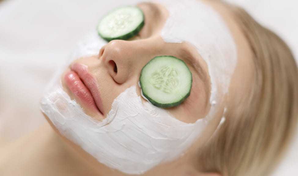 Woman relaxing with a face mask and cucumber slices on eyes.